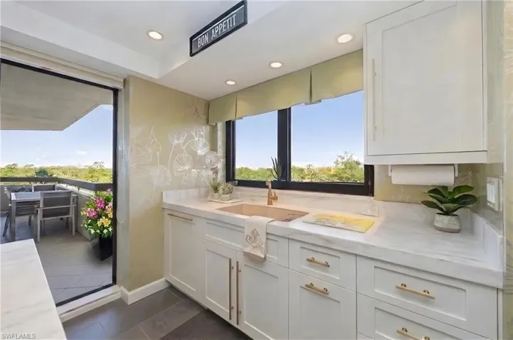 Kitchenette with white shaker cabinetry, white countertops, and gold-finish hardware