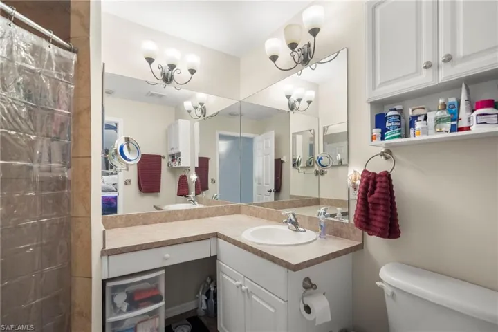 Bathroom featuring vanity, curtained shower, toilet, and an inviting chandelier