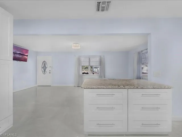 Kitchen with white cabinets, light stone countertops, and open floor plan