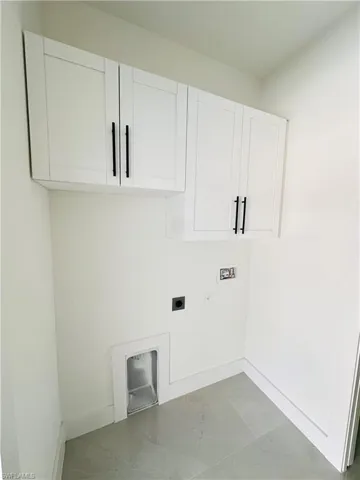 Laundry room with marble finish floor, hookup for a washing machine, cabinet space, electric dryer hookup, and baseboards