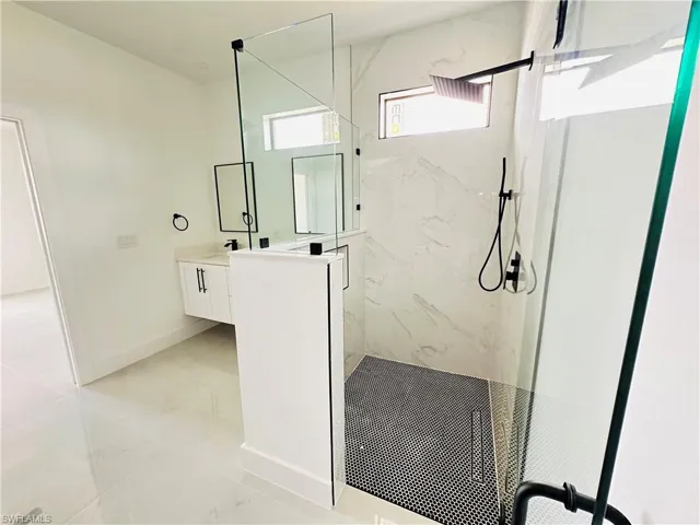 Full bath featuring marble finish floor, a marble finish shower, baseboards, and vanity