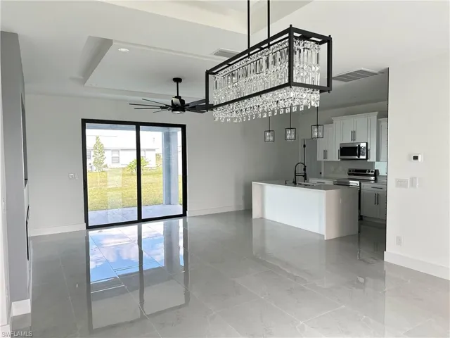 Kitchen with open floor plan, stainless steel appliances, an island with sink, and white cabinets