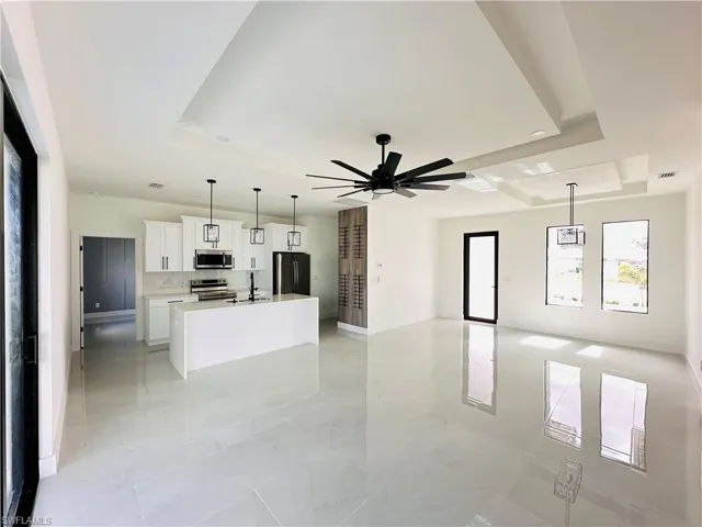 Kitchen with open floor plan, stainless steel appliances, an island with sink, and white cabinets