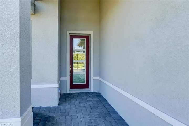 View of exterior entry featuring a shingled roof and stucco siding