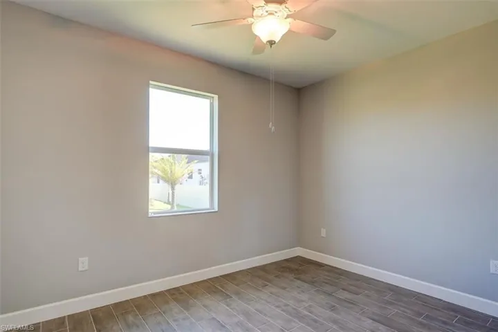 Unfurnished room featuring wood finished floors, a ceiling fan, and baseboards