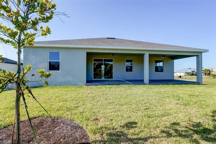 Rear view of house featuring a patio area, a lawn, a ceiling fan, and stucco siding