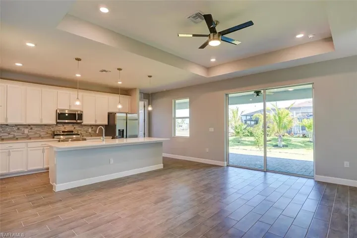 Kitchen with stainless steel appliances, a raised ceiling, and light countertops