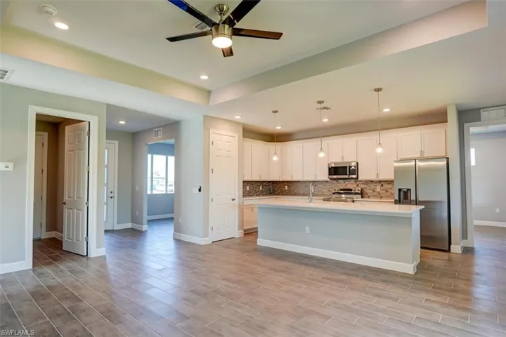 Kitchen with pendant lighting, tasteful backsplash, light countertops, appliances with stainless steel finishes, and white cabinetry