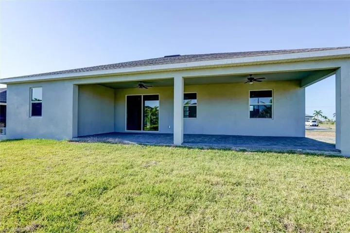 Back of property featuring a lawn, a patio area, a ceiling fan, and stucco siding