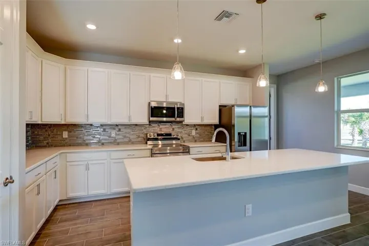 Kitchen with visible vents, white cabinets, appliances with stainless steel finishes, light countertops, and a sink