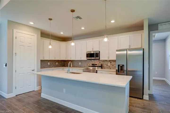 Kitchen featuring appliances with stainless steel finishes, white cabinets, light countertops, and a sink