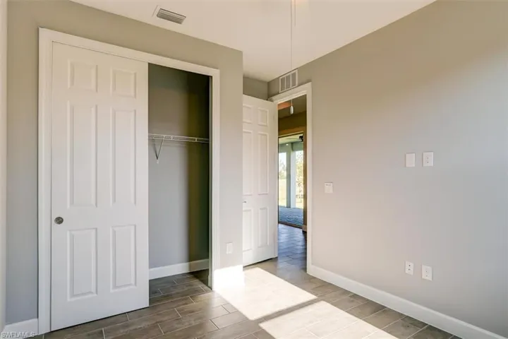 Unfurnished bedroom featuring wood finish floors, a closet, visible vents, and baseboards