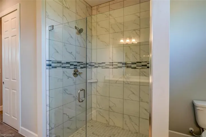 Full bathroom featuring toilet, a stall shower, and baseboards