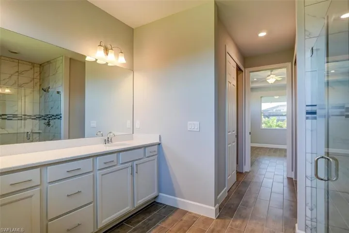 Full bathroom featuring a shower stall, vanity, baseboards, and wood finish floors