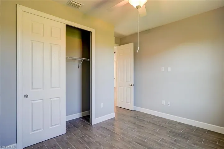 Unfurnished bedroom with a ceiling fan, baseboards, visible vents, a closet, and wood tiled floor