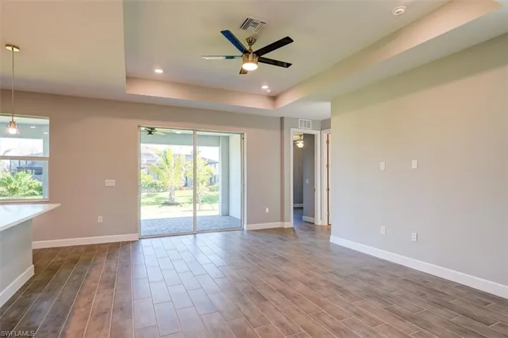 Unfurnished room with ceiling fan, a tray ceiling, and wood finished floors
