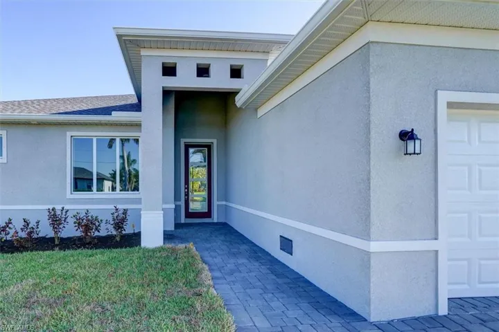Property entrance featuring an attached garage, a shingled roof, and stucco siding