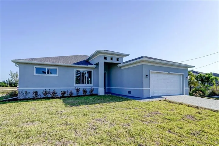 View of front of house featuring a garage, a front lawn, decorative driveway, and stucco siding
