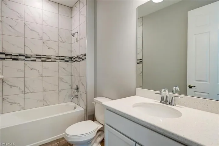 Full bathroom featuring toilet, washtub / shower combination, wood finished floors, and vanity