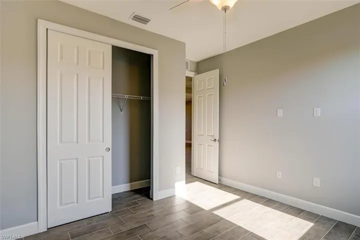 Unfurnished bedroom with a ceiling fan, wood tiled floor, a closet, and baseboards