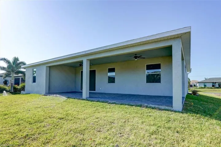 Back of property with a yard, stucco siding, a ceiling fan, and a patio
