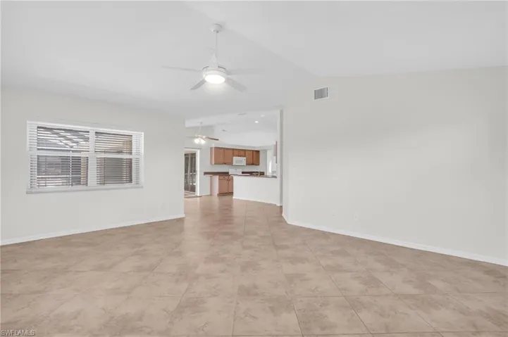 Large family room with lofted ceiling, light tile floors, and ceiling fan
