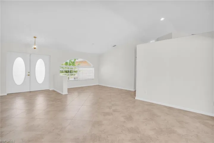 Tiled entryway featuring lofted ceiling and french doors