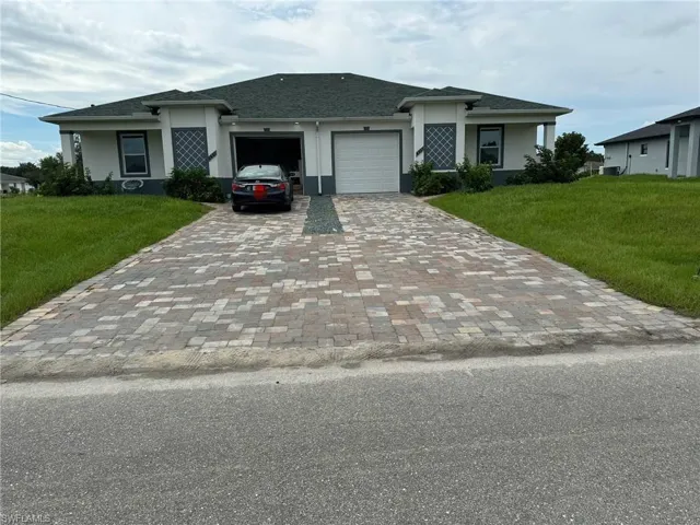 View of front facade featuring a garage and a front lawn