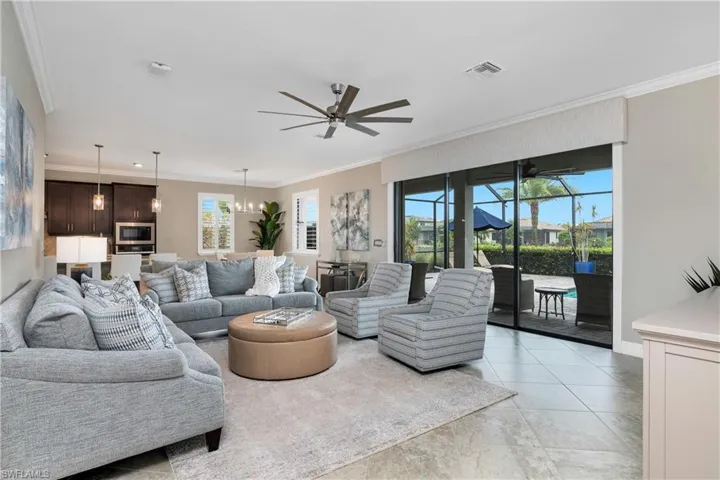 Living room with a wealth of natural light, crown molding, light tile floors, and ceiling fan