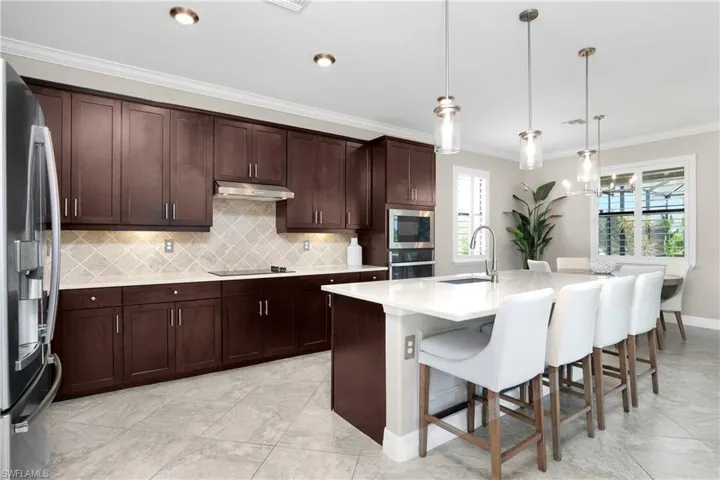 Kitchen with hanging light fixtures, a center island with sink, tasteful backsplash, appliances with stainless steel finishes, and sink