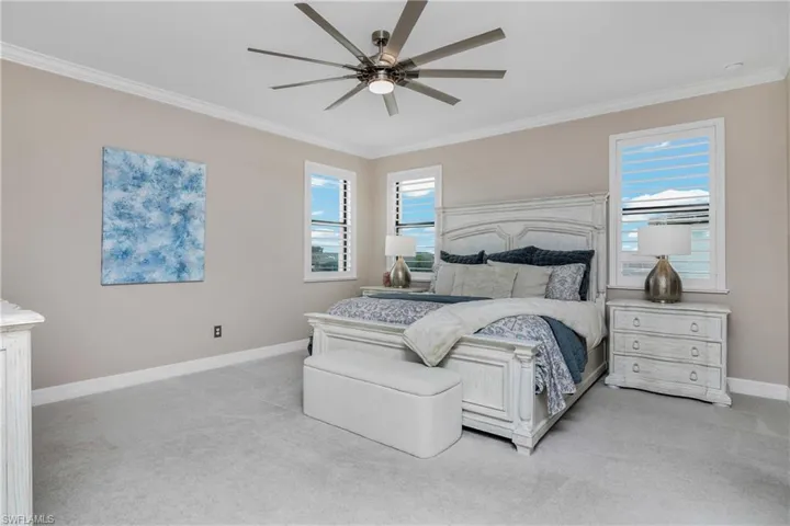 Bedroom with crown molding, ceiling fan, and light colored carpet
