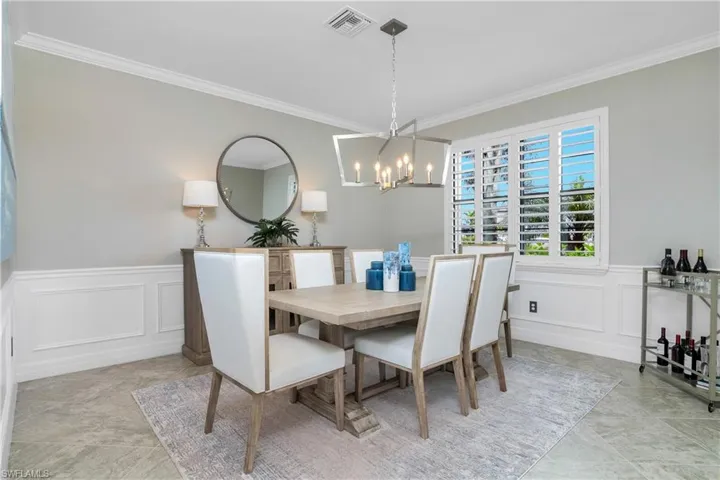 Dining space featuring a notable chandelier, crown molding, and light tile floors