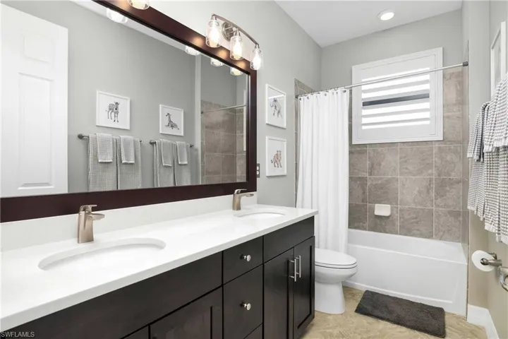 Full bathroom with oversized vanity, toilet, tile flooring, double sink, and shower / tub combo