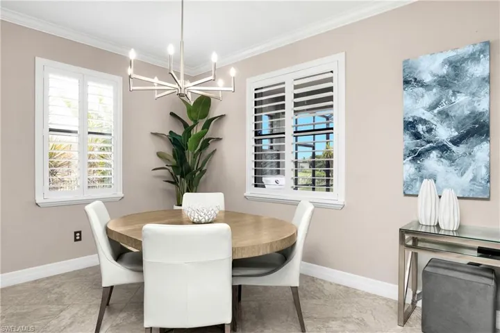 Tiled dining space with crown molding and a chandelier