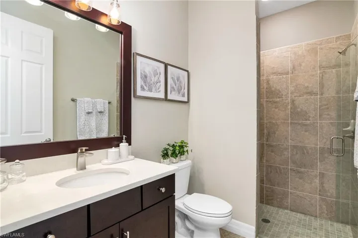 Bathroom featuring walk in shower, vanity, and toilet