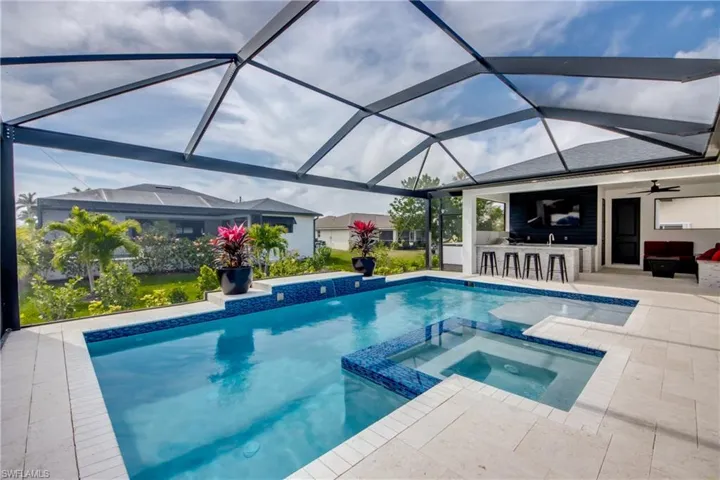 view of outdoor pool, with connected spa, lounge area, outdoor wet bar, and glass enclosures