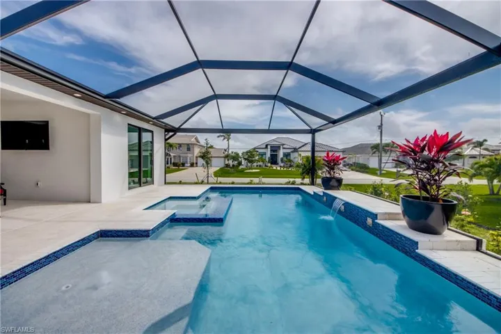 view of outdoor pool, with water feature, connected spa and lounge pad.