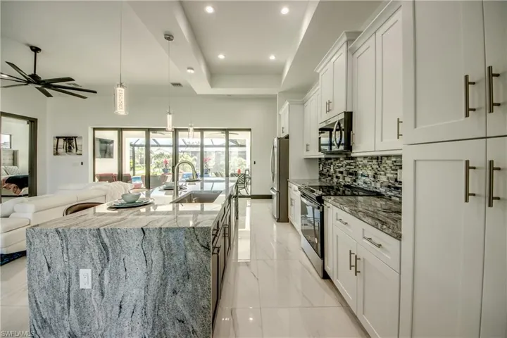 tchen with an island featuring a "waterfall" granite top- tasteful backsplash, stainless steel finishes, and marble floord.