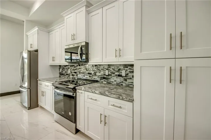 view of our custom soft close cabinets- featuring , tasteful backsplash, and marble flooring