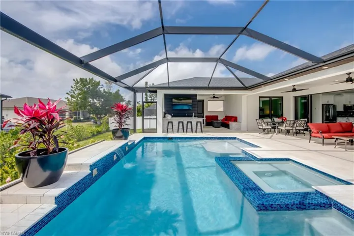 view of outdoor pool, with connected spa, lounge area, outdoor wet bar, and glass enclosures