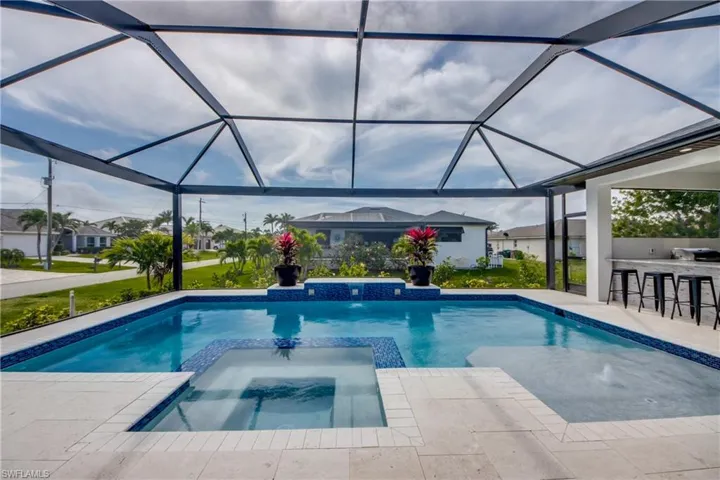 view of outdoor pool, with water feature, connected spa and lounge pad.