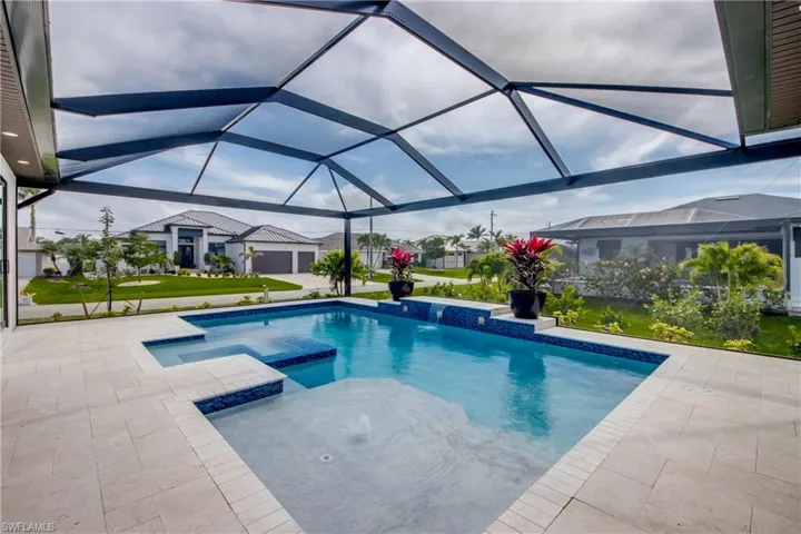 view of outdoor pool, with water feature, connected spa and lounge pad.