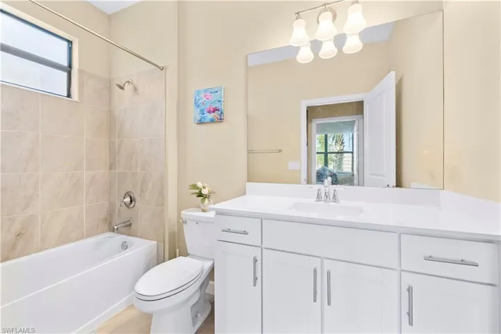 Bathroom with shower / bathing tub combination, vanity, toilet, and a wealth of natural light