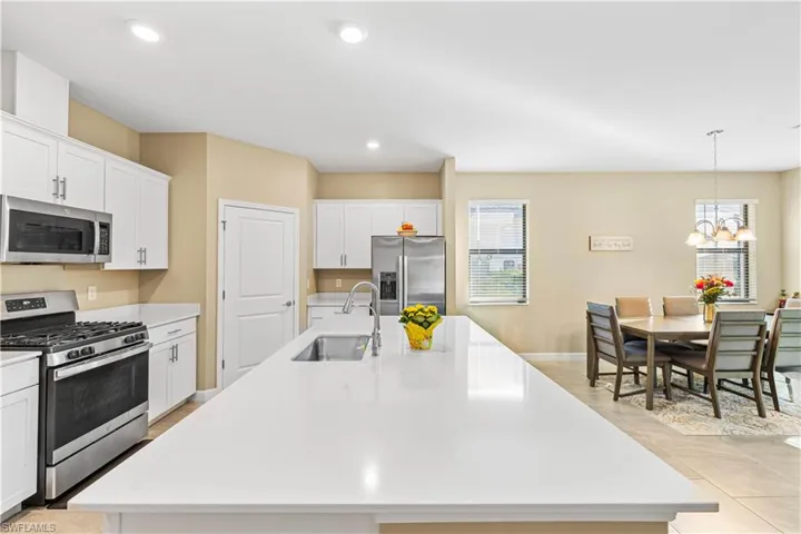 Kitchen with a sink, a center island with sink, light countertops, and appliances with stainless steel finishes