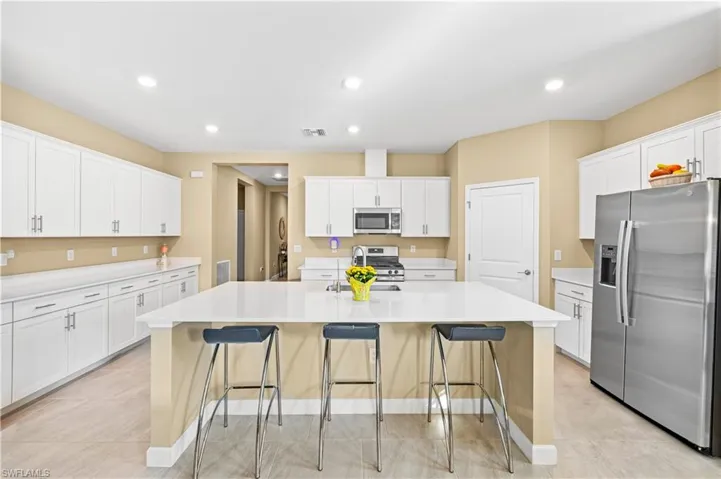 Kitchen featuring a breakfast bar area, visible vents, a sink, white cabinetry, and appliances with stainless steel finishes