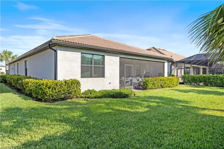 Back of house featuring a yard, stucco siding, and a tiled roof
