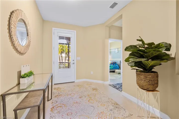 Foyer entrance with light tile patterned floors, baseboards, and visible vents