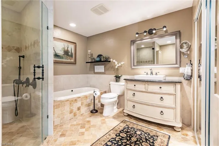 Full bathroom with tile floors, oversized vanity, toilet, and separate shower and tub