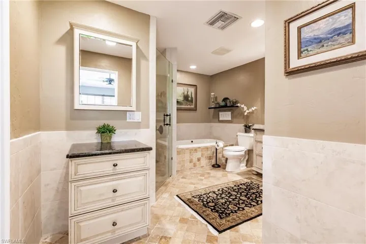 Full bathroom featuring tile floors, plus walk in shower, tub, vanity, and toilet