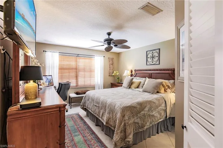 Master Bedroom with a textured ceiling, ceiling fan, and tile floors